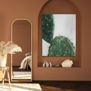 a painting of a cactus hangs on a wall next to a mirror