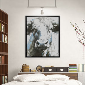 a picture of a cow hangs above a bed