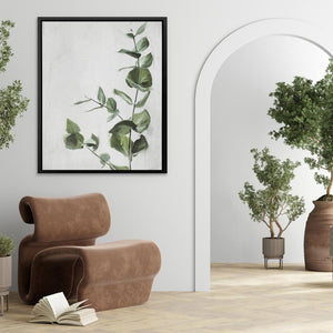 a living room with a chair, potted plant and a framed picture