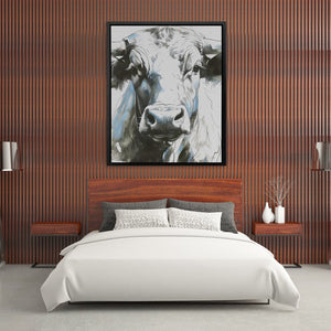 a picture of a cow hangs above a bed